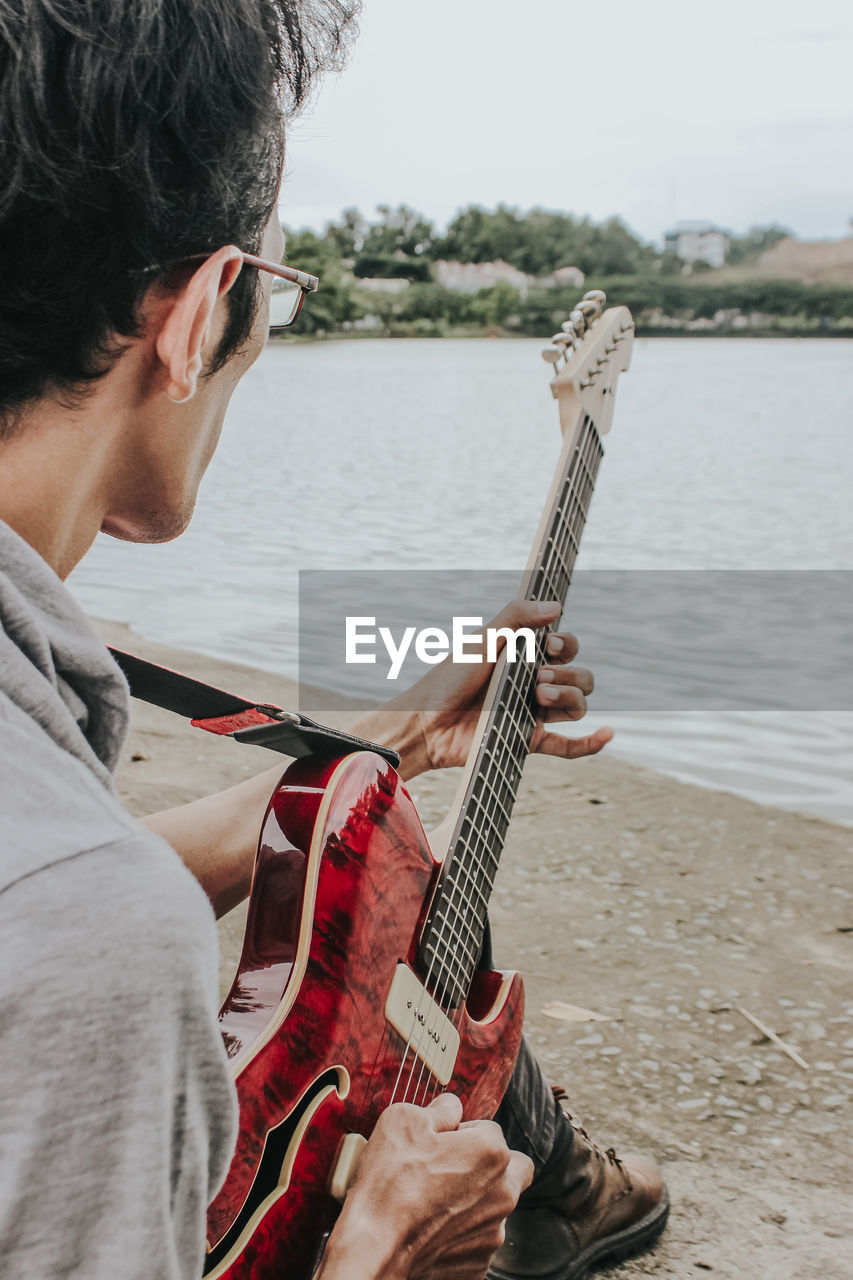 Man playing guitar on riverbank