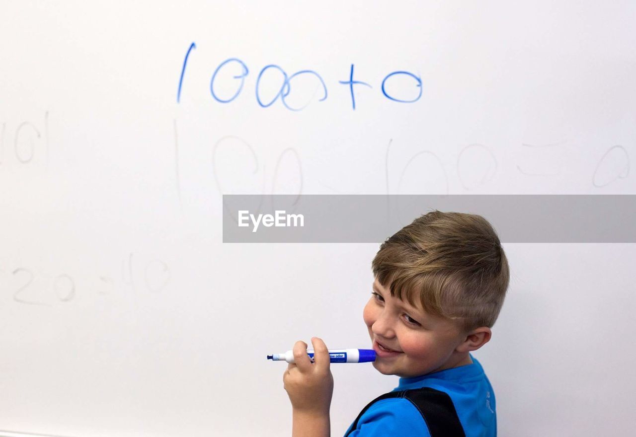 CLOSE-UP OF A BOY WITH TEXT AGAINST WALL