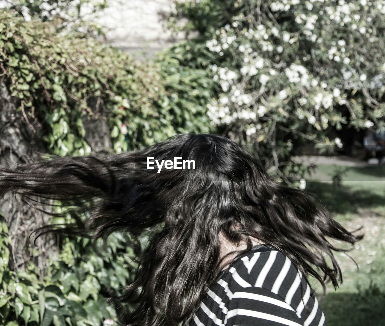 Woman with tousled hair against trees in park