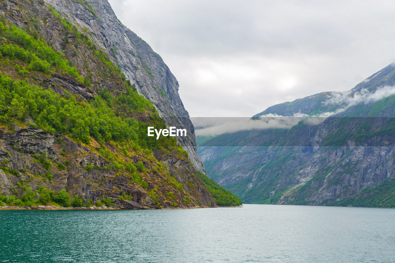 Scenic view of mountains and sea against cloudy sky