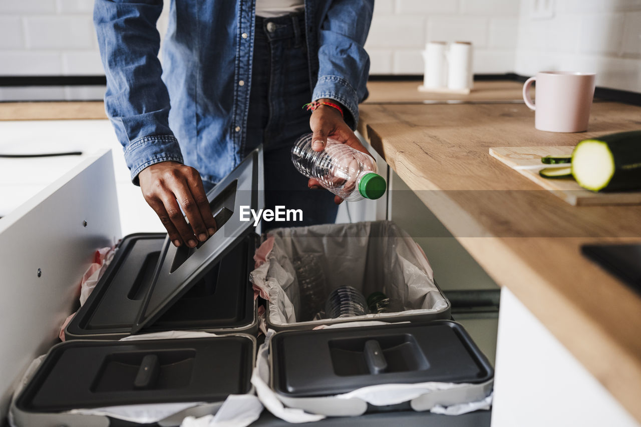 Woman recycling plastic bottles in kitchen at home