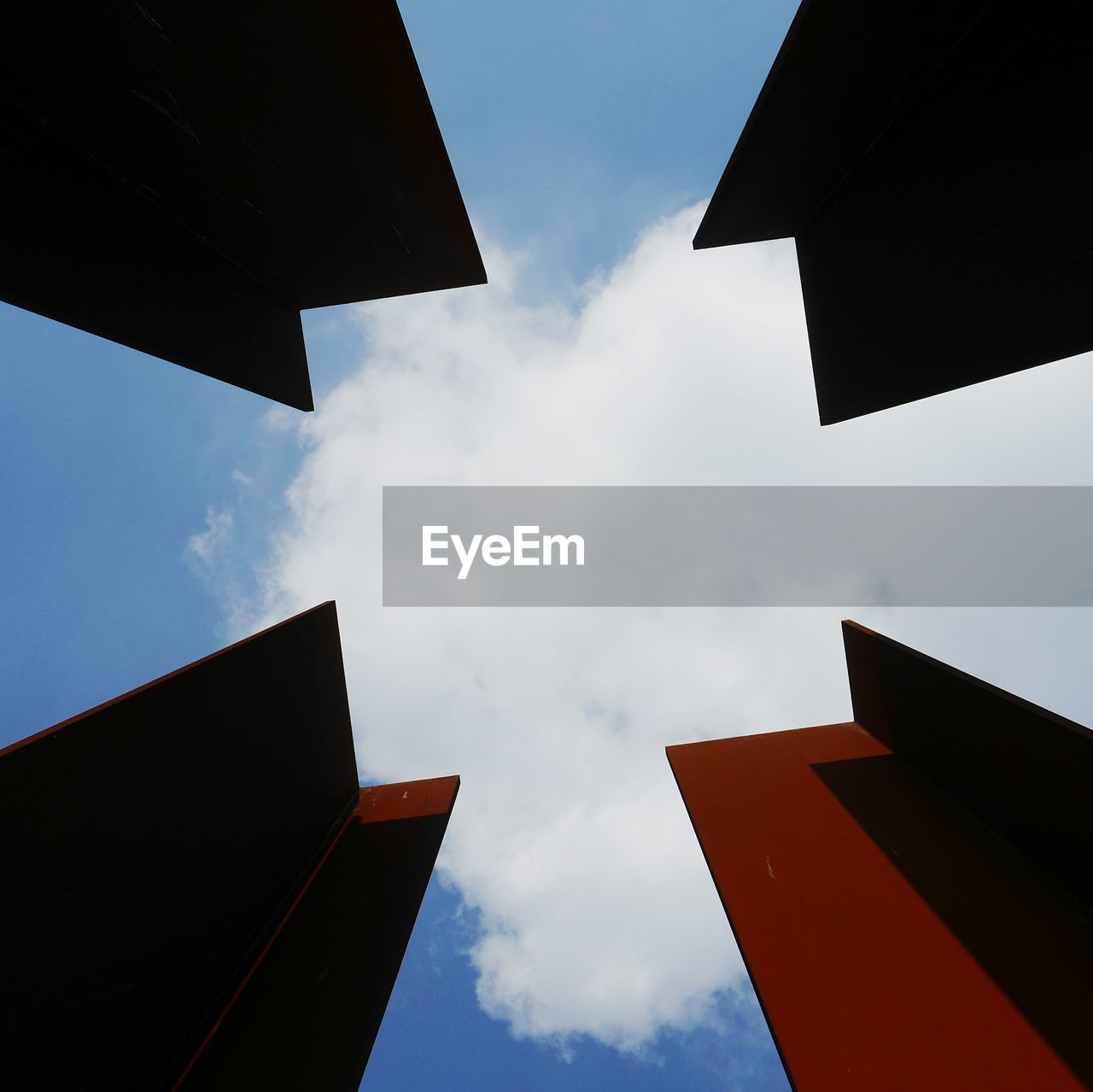 Directly below shot of built structures against cloudy blue sky