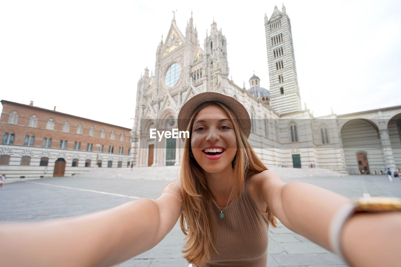 Holidays in italy. brazilian girl takes selfie picture with smartphone in siena, tuscany, italy.