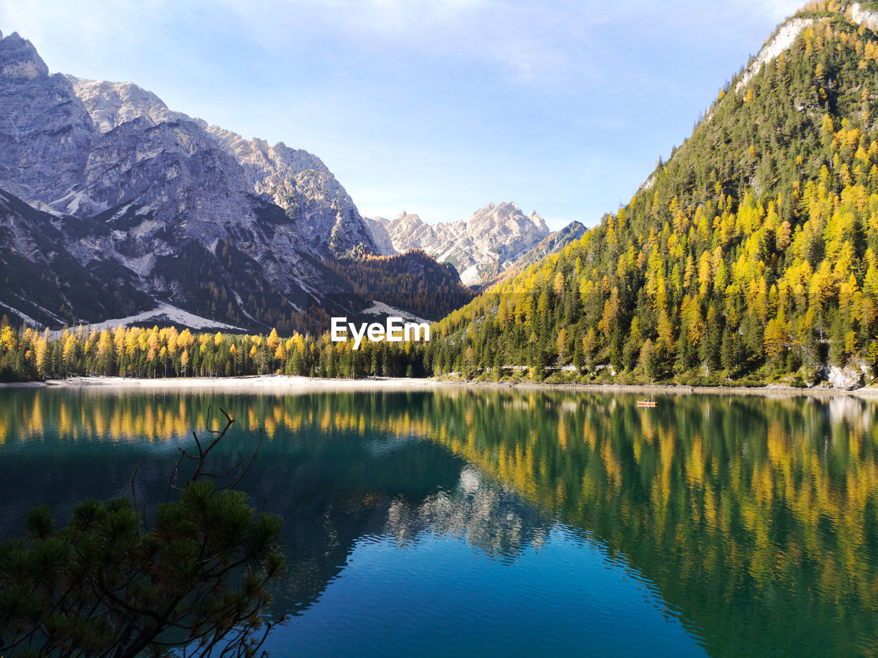 Natural landscape of braies lake with green trees, lake with reflection and mountain with snow