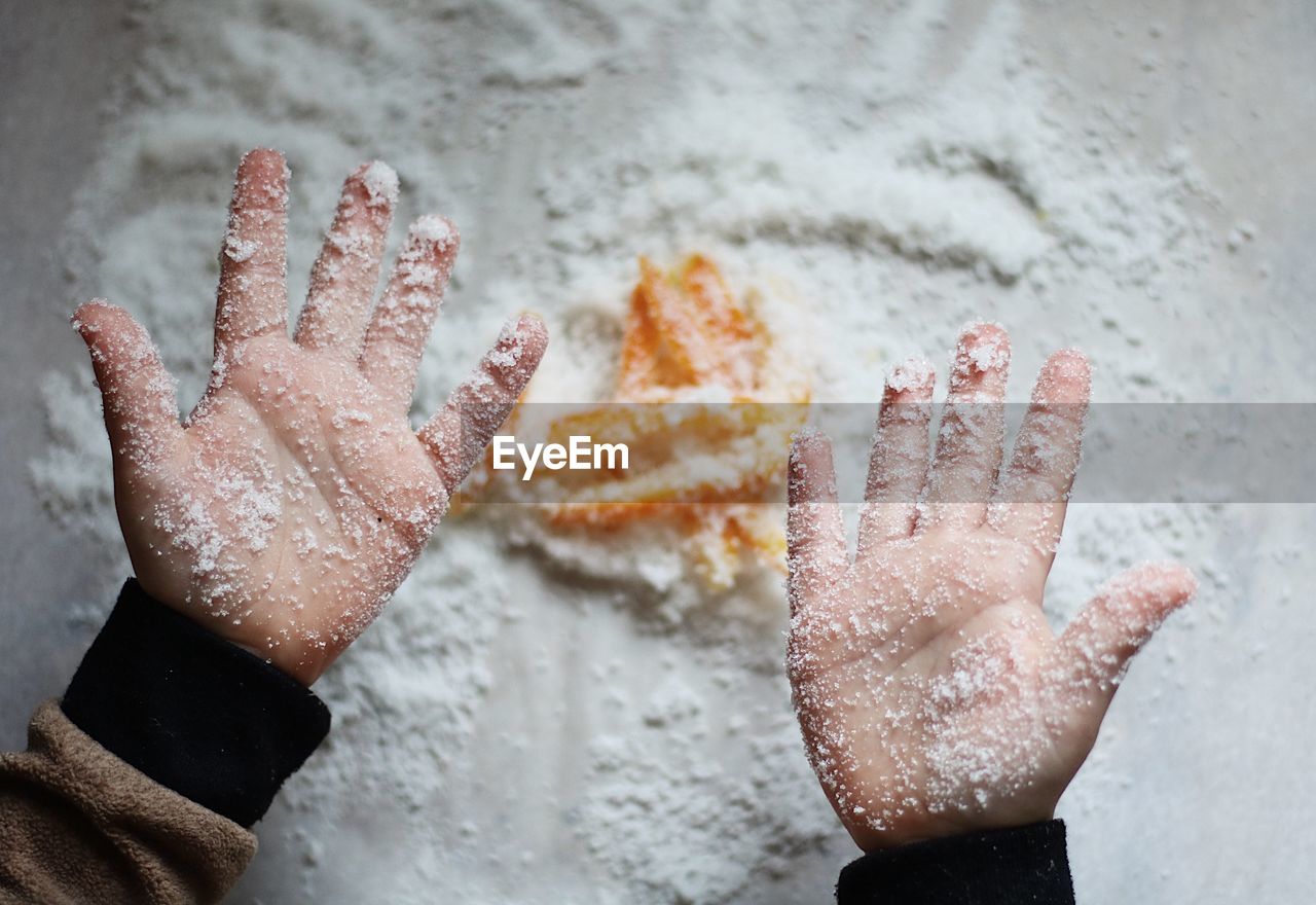 High angle view of childs hands covered in sugar