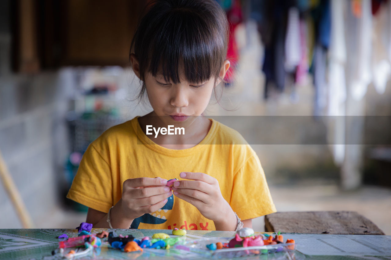 Cute girl playing with clay at home