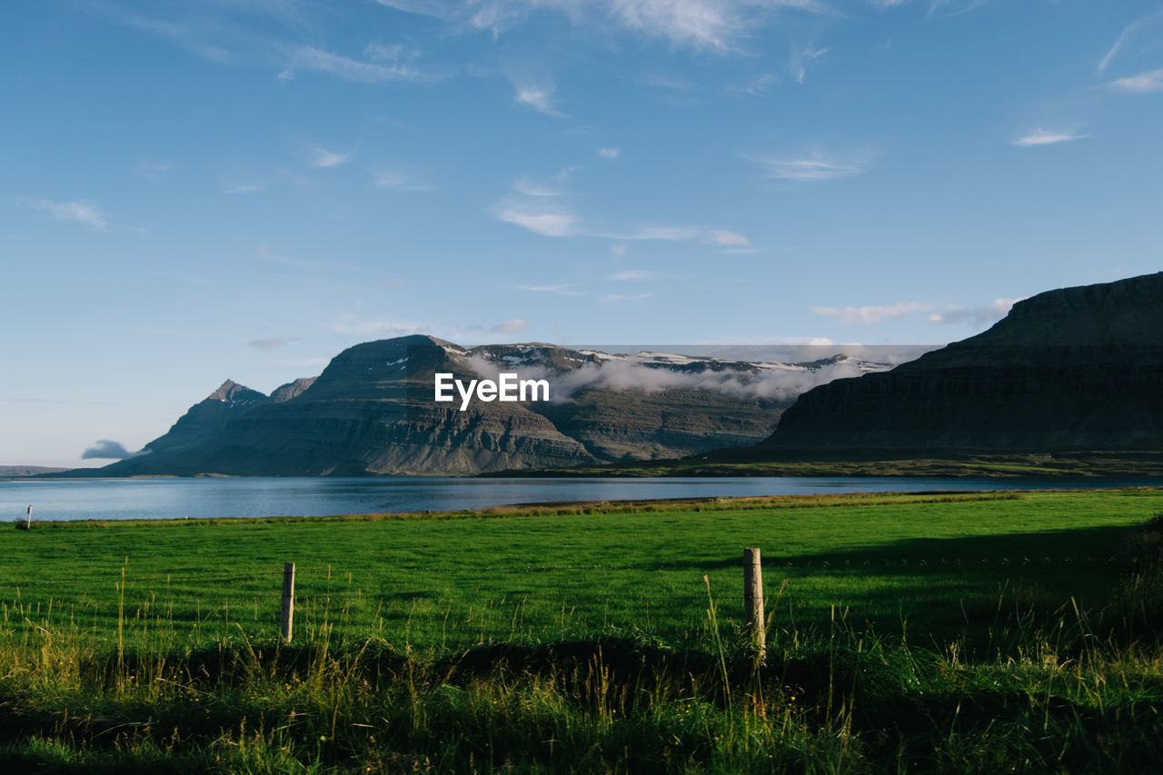 Scenic view of river by mountains against sky