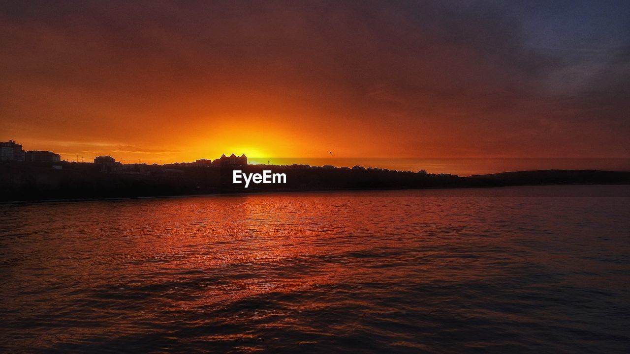 Scenic view of sea against dramatic sky during sunset