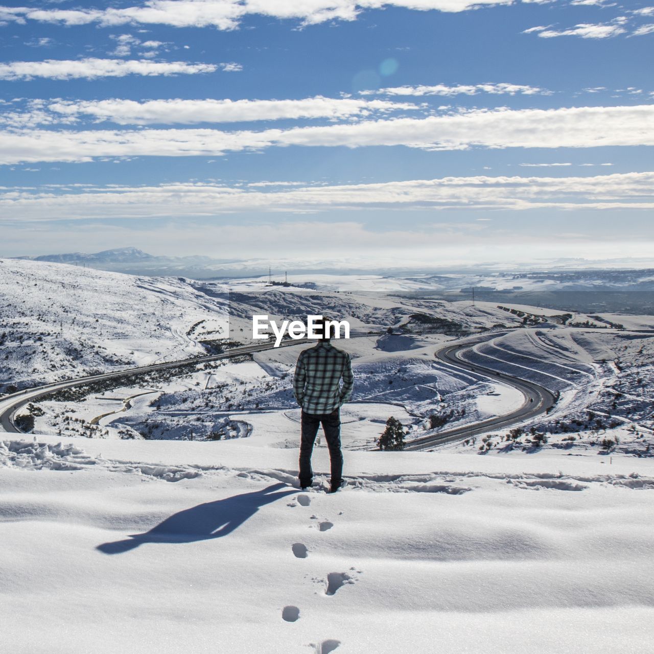Rear view of man standing on snowcapped mountain