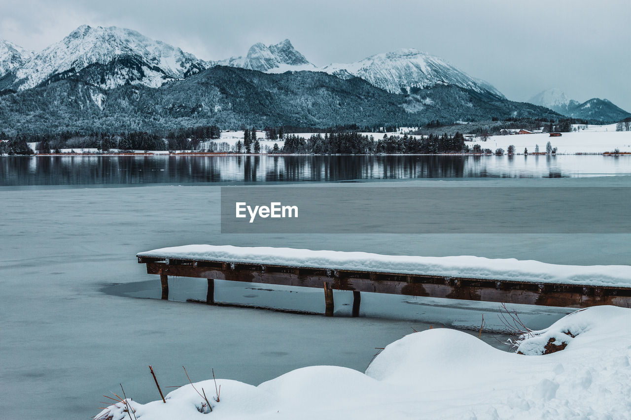 The hopfensee with the allgäu alps in winter. germany. in the foreground snow-covered jetty.