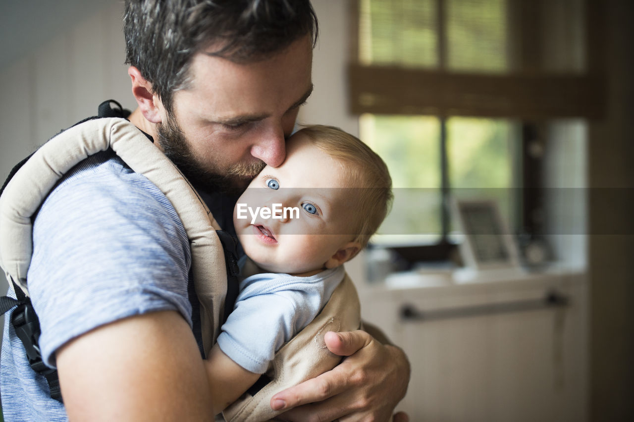 Father cuddling with baby in baby carrier