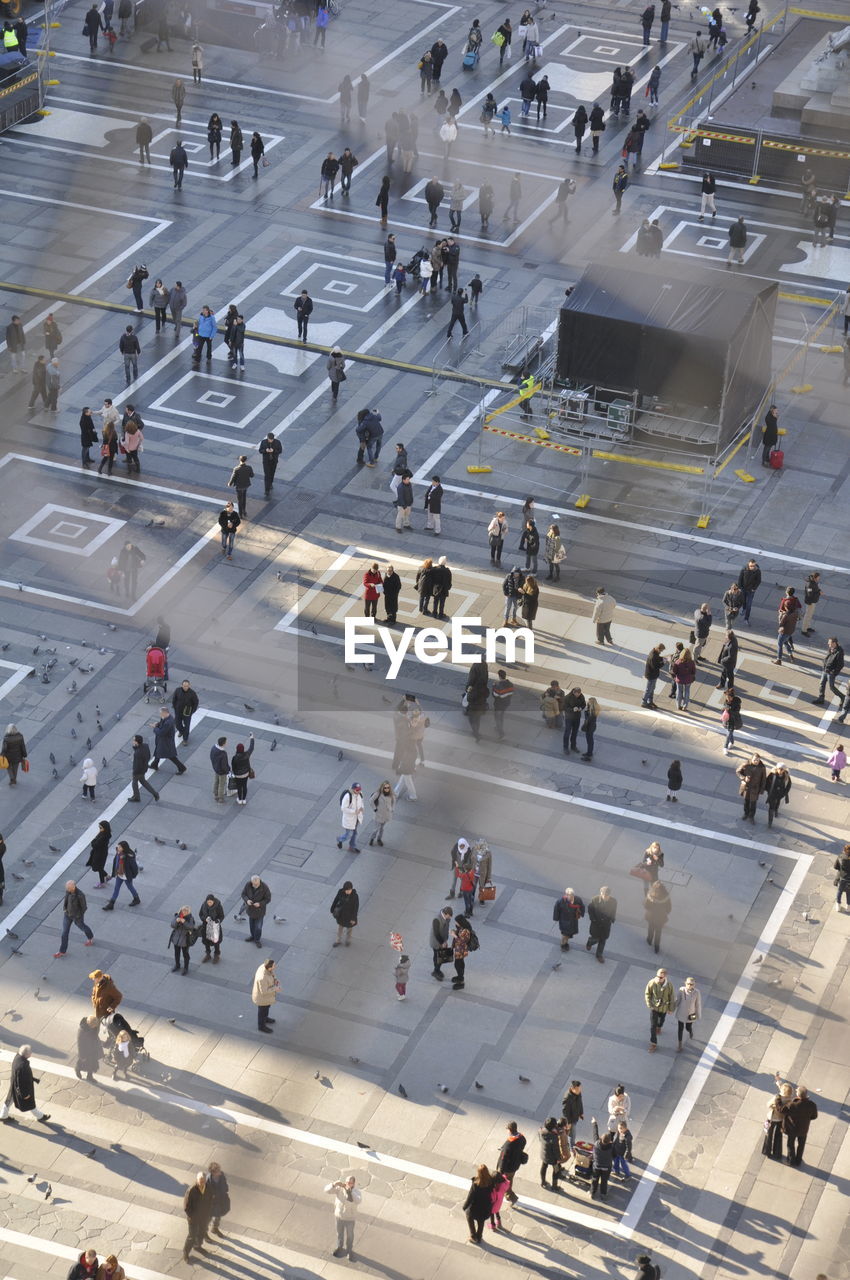 HIGH ANGLE VIEW OF GROUP OF PEOPLE WALKING ON ROAD IN CITY