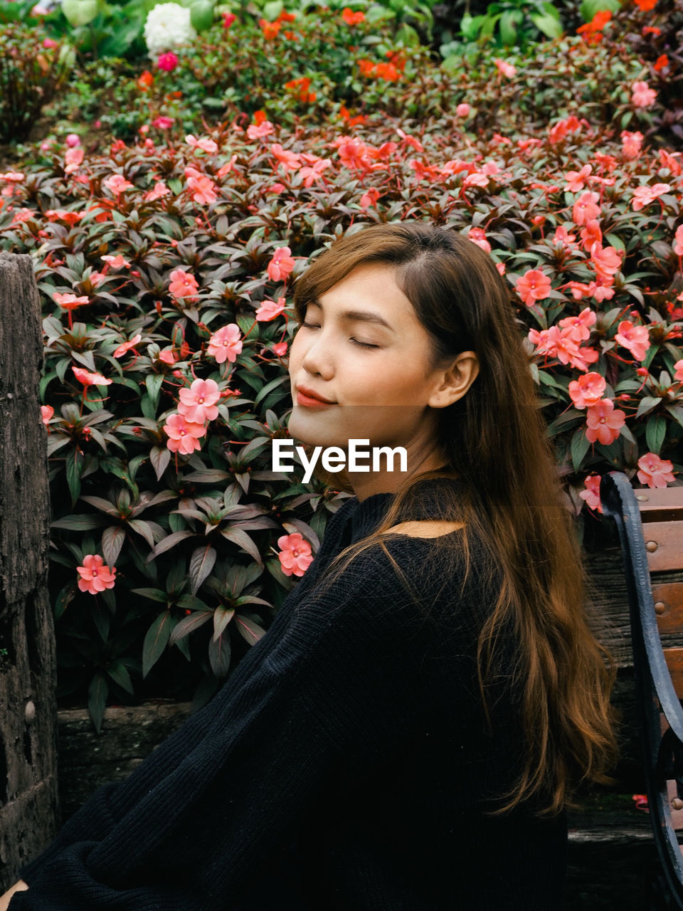 Beautiful woman with closed eyes standing by flowering plants