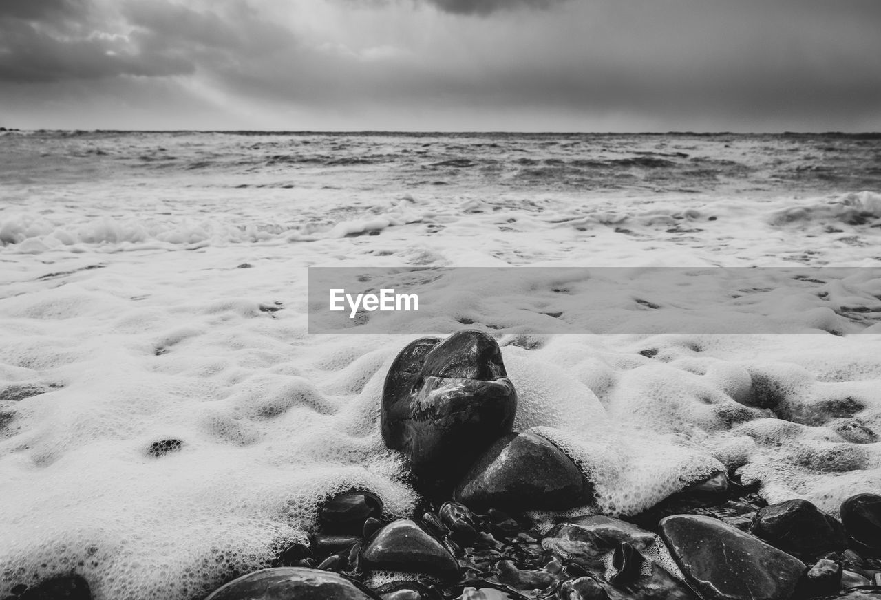 land, beach, sea, sky, rock, black and white, water, wave, ocean, monochrome, cloud, nature, sand, monochrome photography, shore, coast, wind wave, beauty in nature, scenics - nature, horizon, horizon over water, environment, no people, outdoors, tranquility, white, sports, motion, day, water sports, winter, body of water, snow