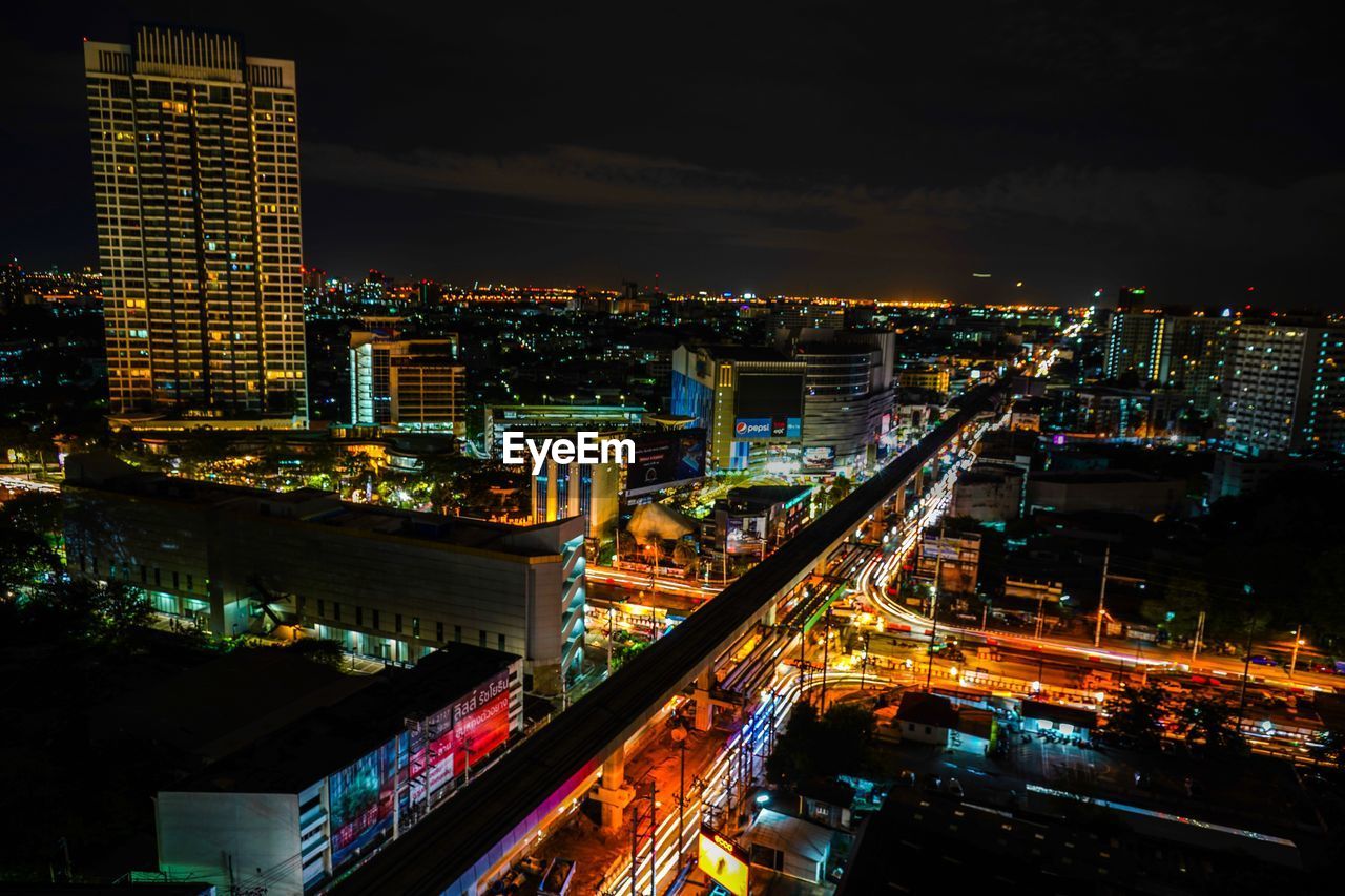 HIGH ANGLE VIEW OF ILLUMINATED STREET AMIDST BUILDINGS IN CITY