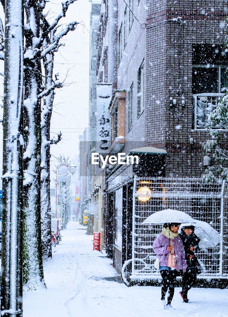 PEOPLE WALKING ON SNOW COVERED CITY DURING WINTER