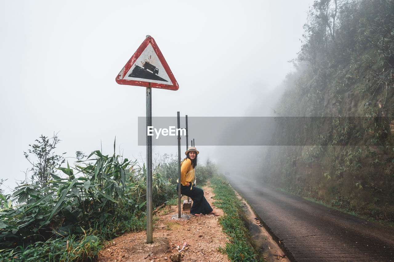 MAN STANDING BY ROAD AGAINST SKY