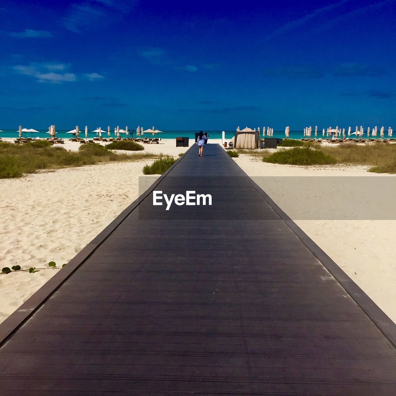 Boardwalk on beach against blue sky