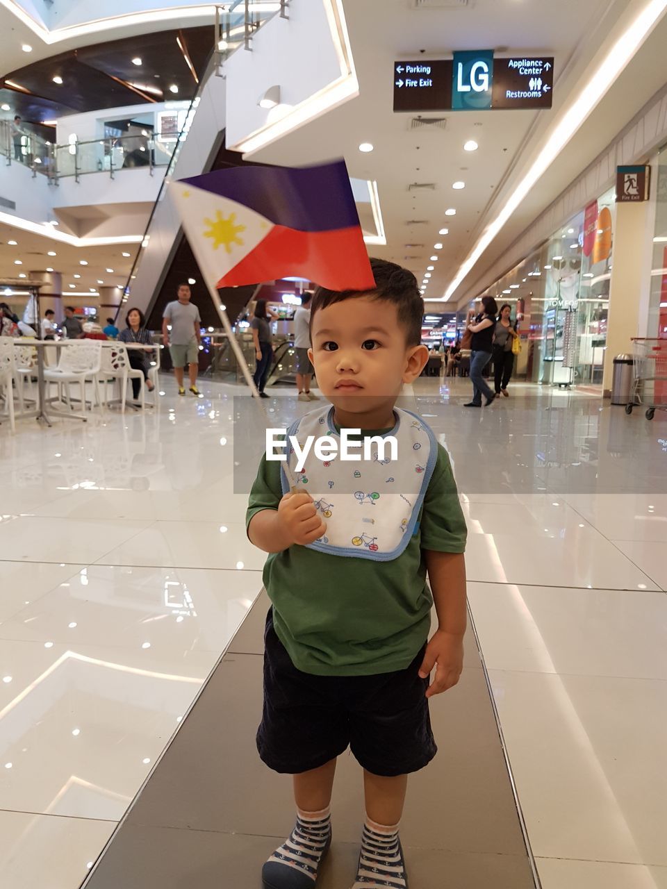 Boy holding philippines flag while standing in shopping mall