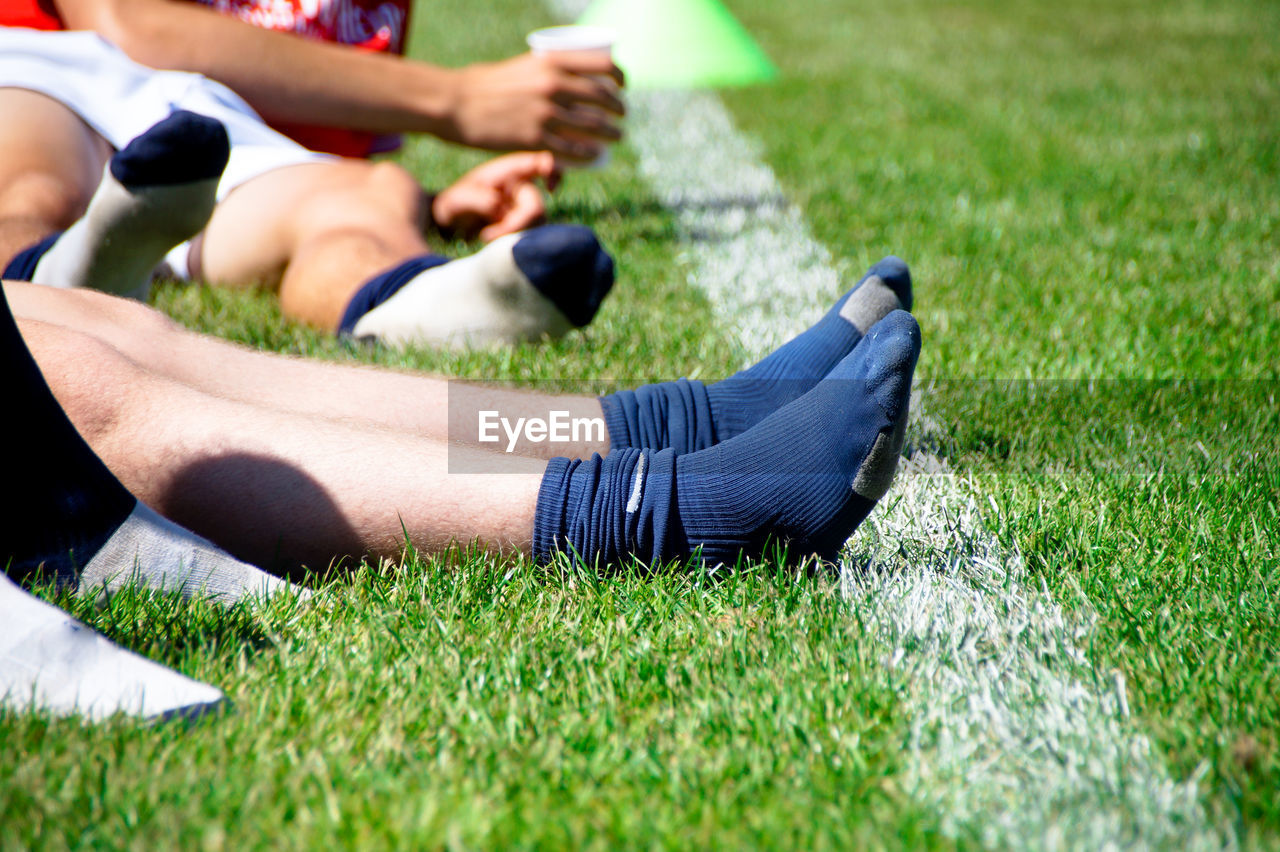 Low section of athletes wearing socks while sitting on field