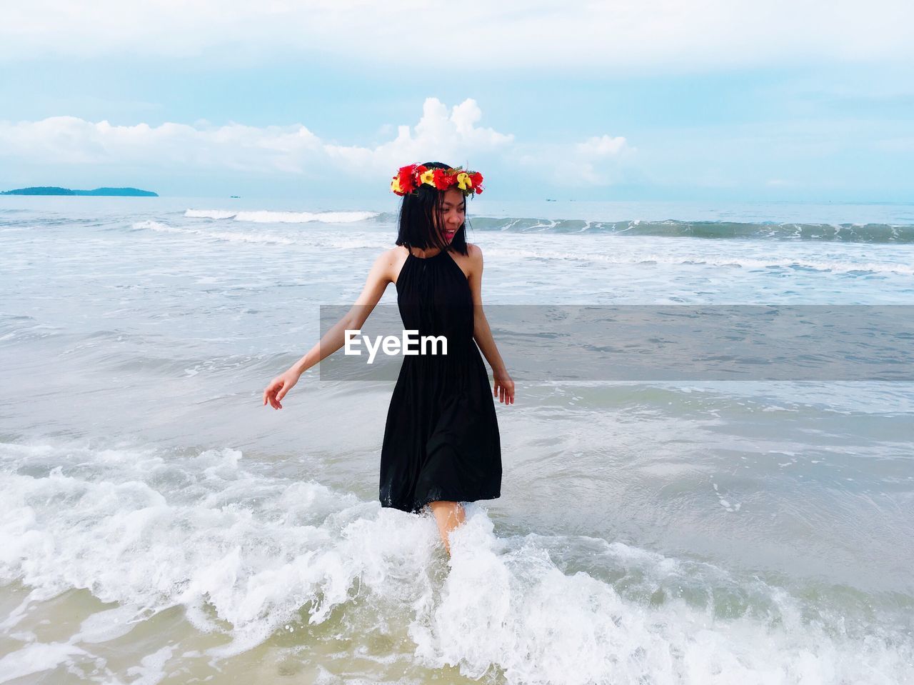 Young woman wearing flower tiara enjoying waves at beach