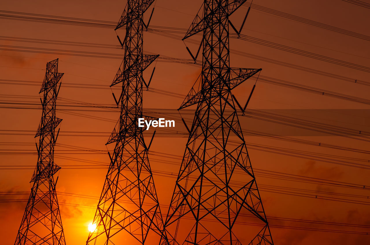 Low angle view of electricity pylon against sky during sunset