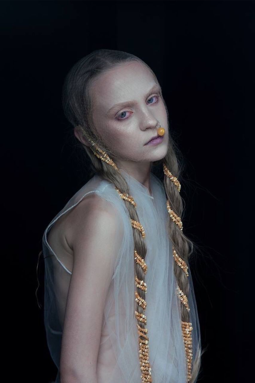 Portrait of young female model standing against black background