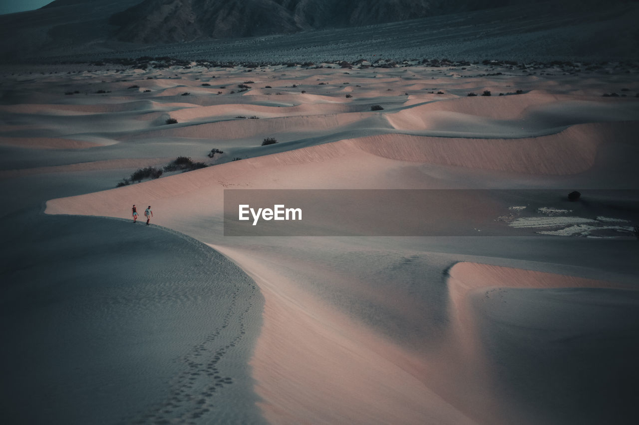 Two people hiking on ridge of sand dune in death valley national park