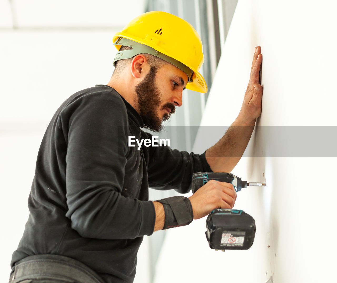 Worker screws plasterboard panels on an aluminum structure.