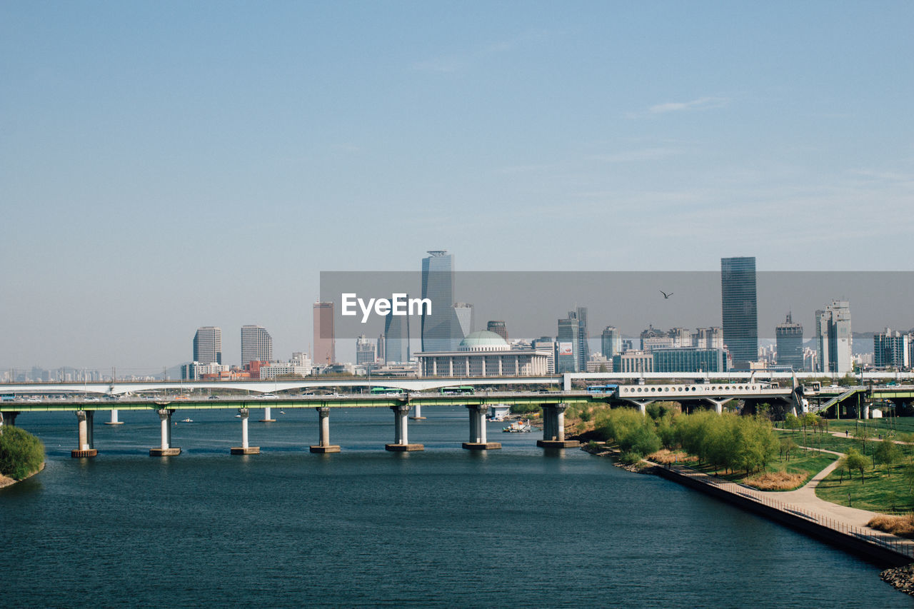 Bridge over river in city against clear sky