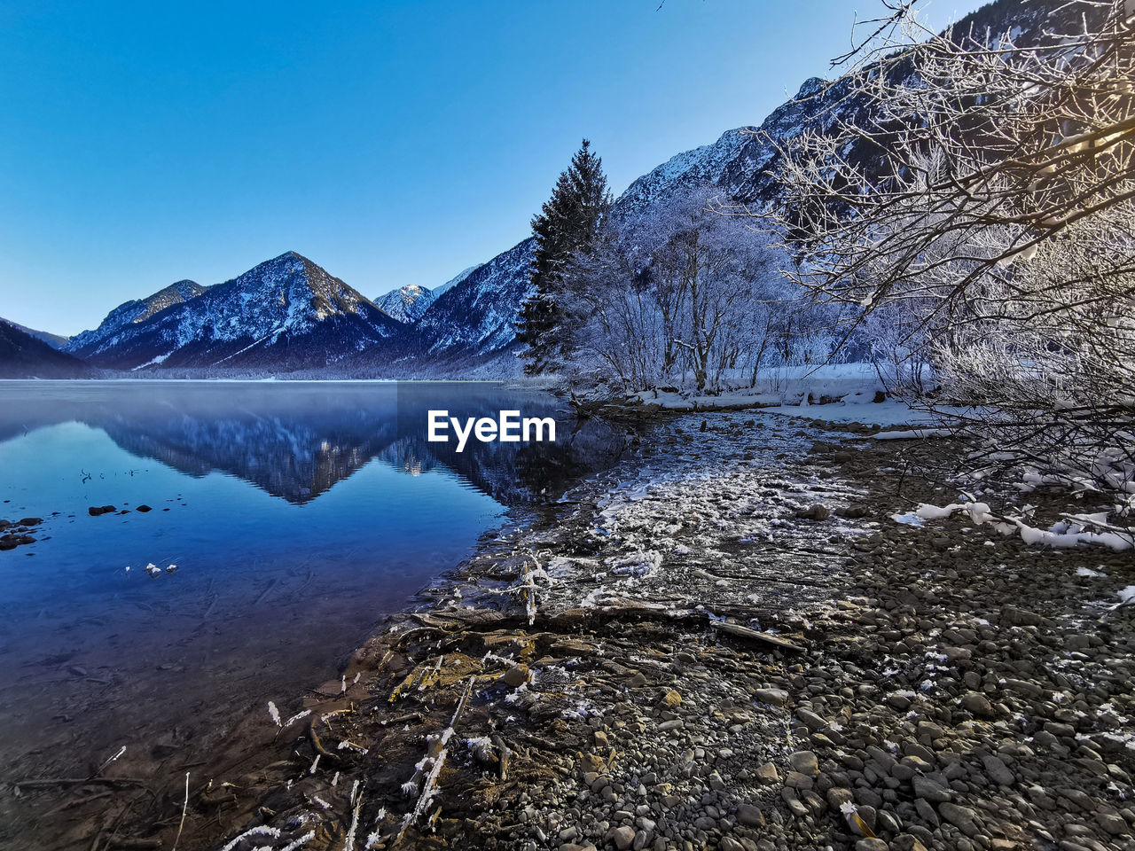 Scenic view of lake by snowcapped mountains against clear sky