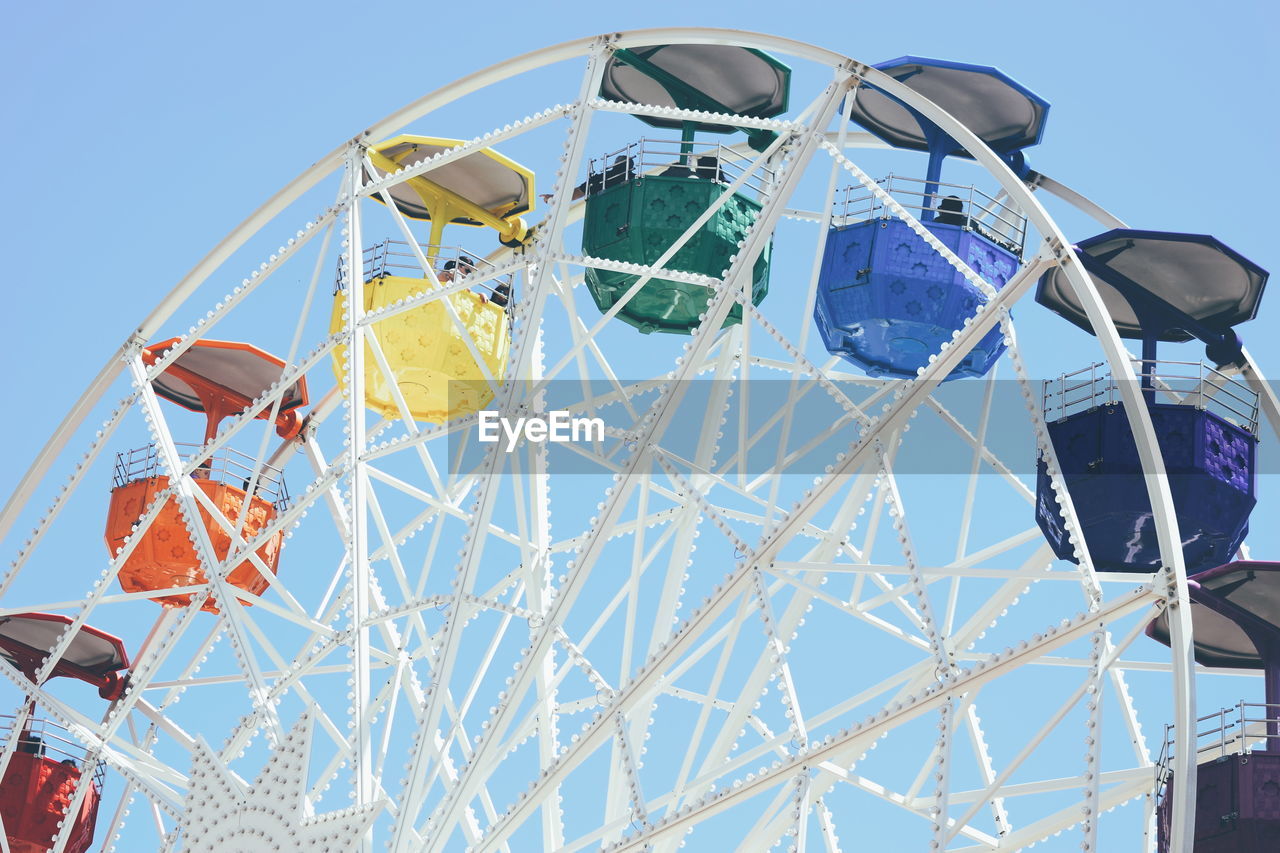 Low angle view of ferris wheel against clear blue sky