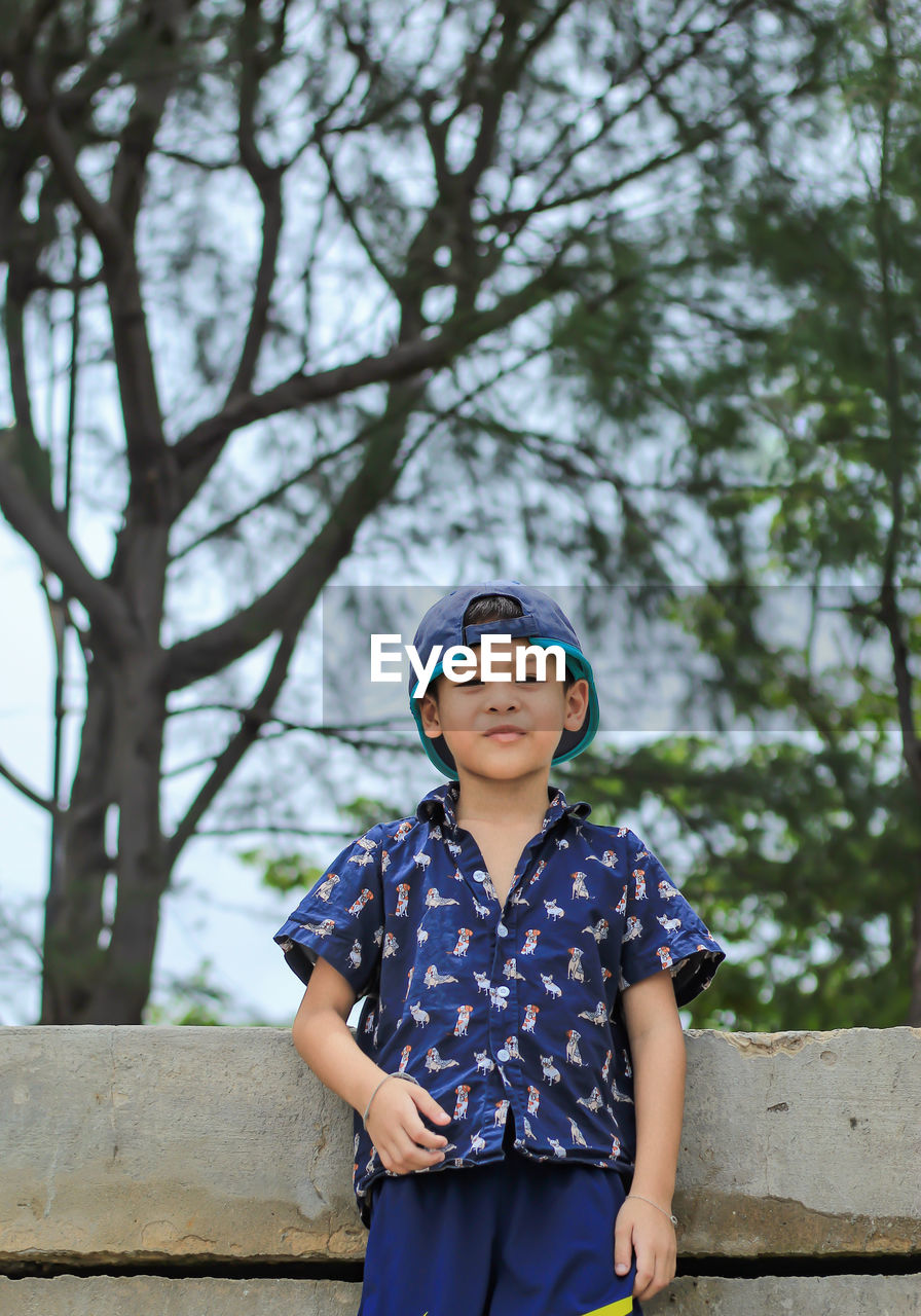 Portrait of smiling boy standing against trees