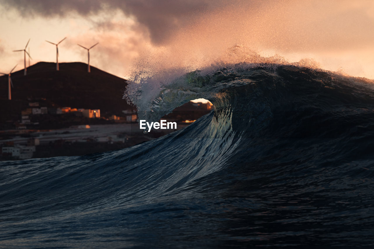 Scenic view of a wave splashing against sky during sunset