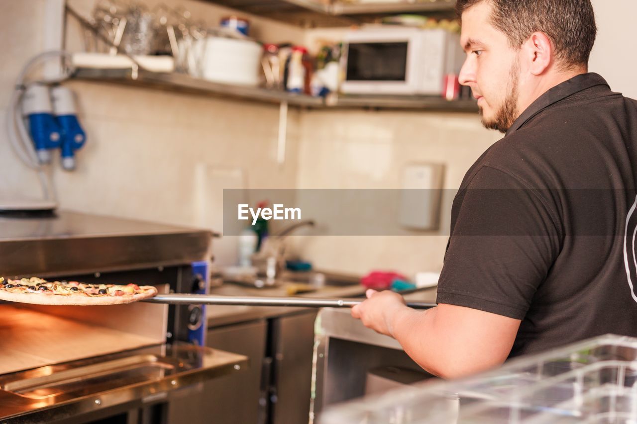 side view of young woman preparing food in kitchen