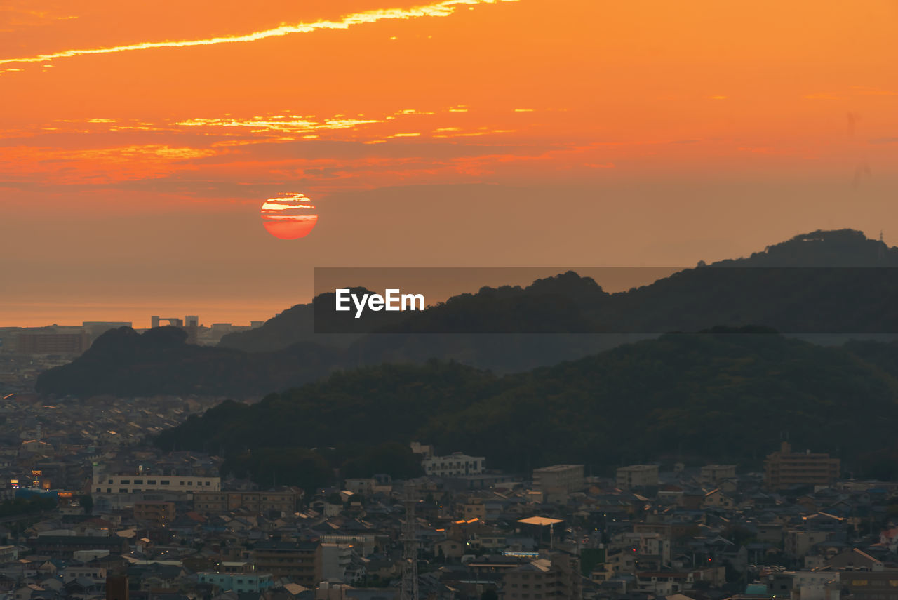 Townscape and mountains against sky during sunset