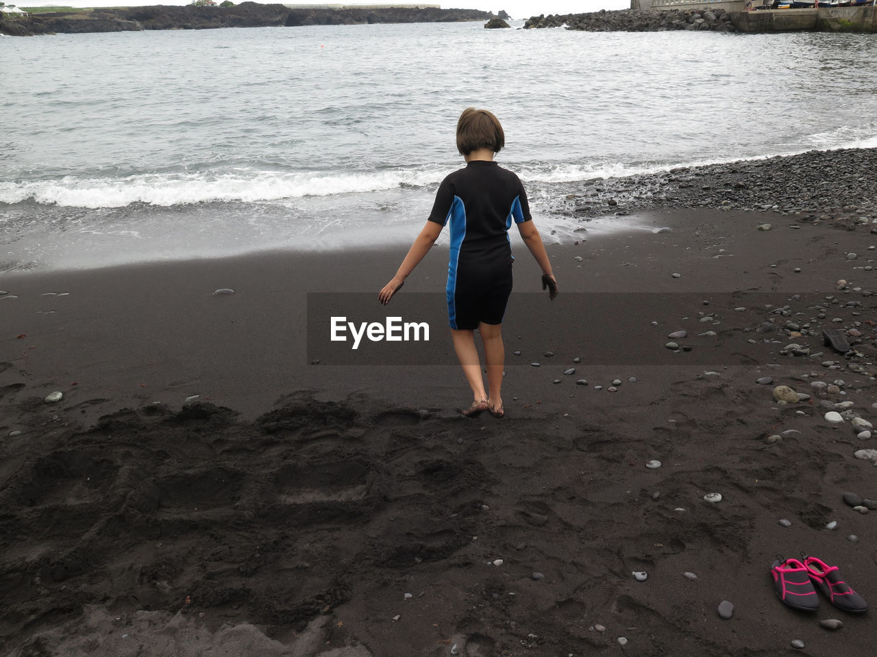 Rear view of girl walking at beach