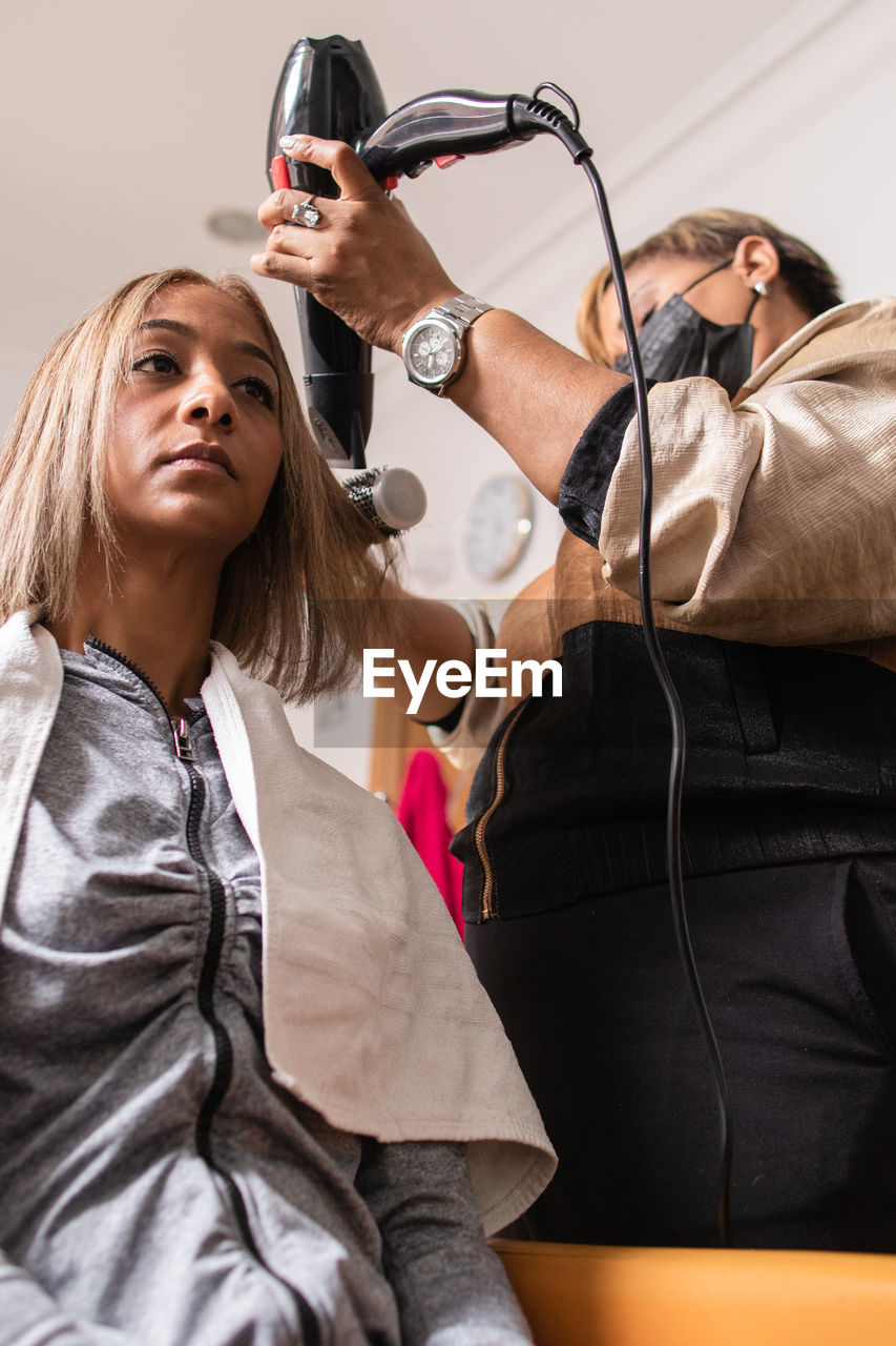 Low angle view of hairdresser styling hair