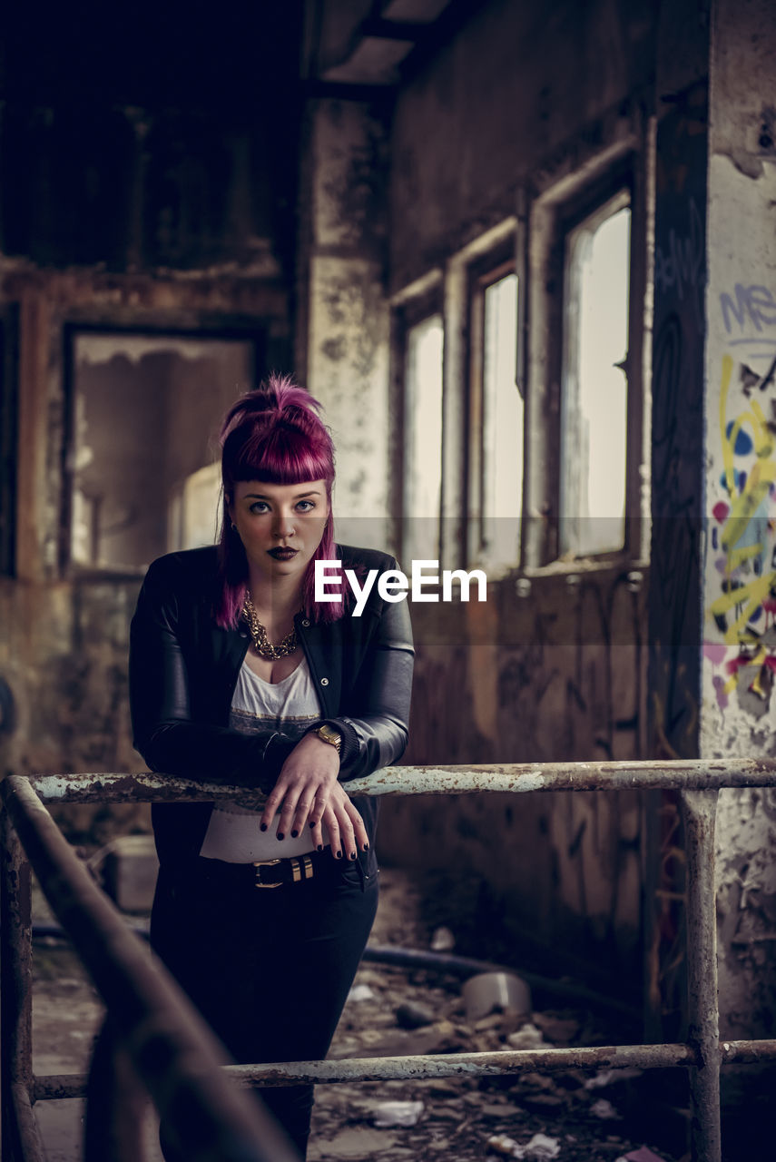 Portrait of woman standing by railing in abandoned building