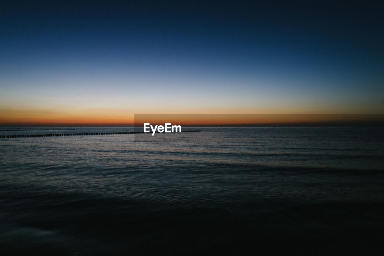 SCENIC VIEW OF SEA AGAINST CLEAR SKY AT DUSK