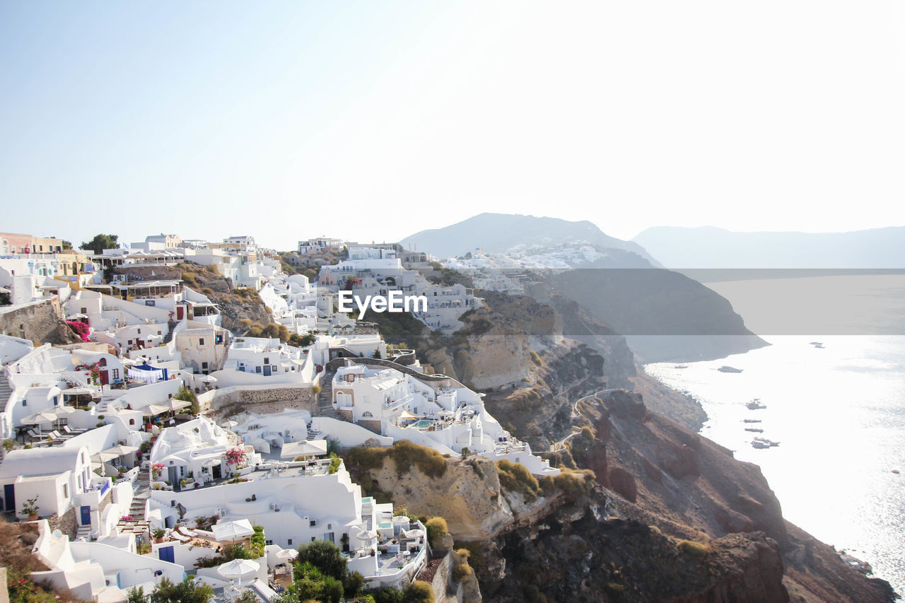 Residential district on mountain by sea against clear sky during foggy weather