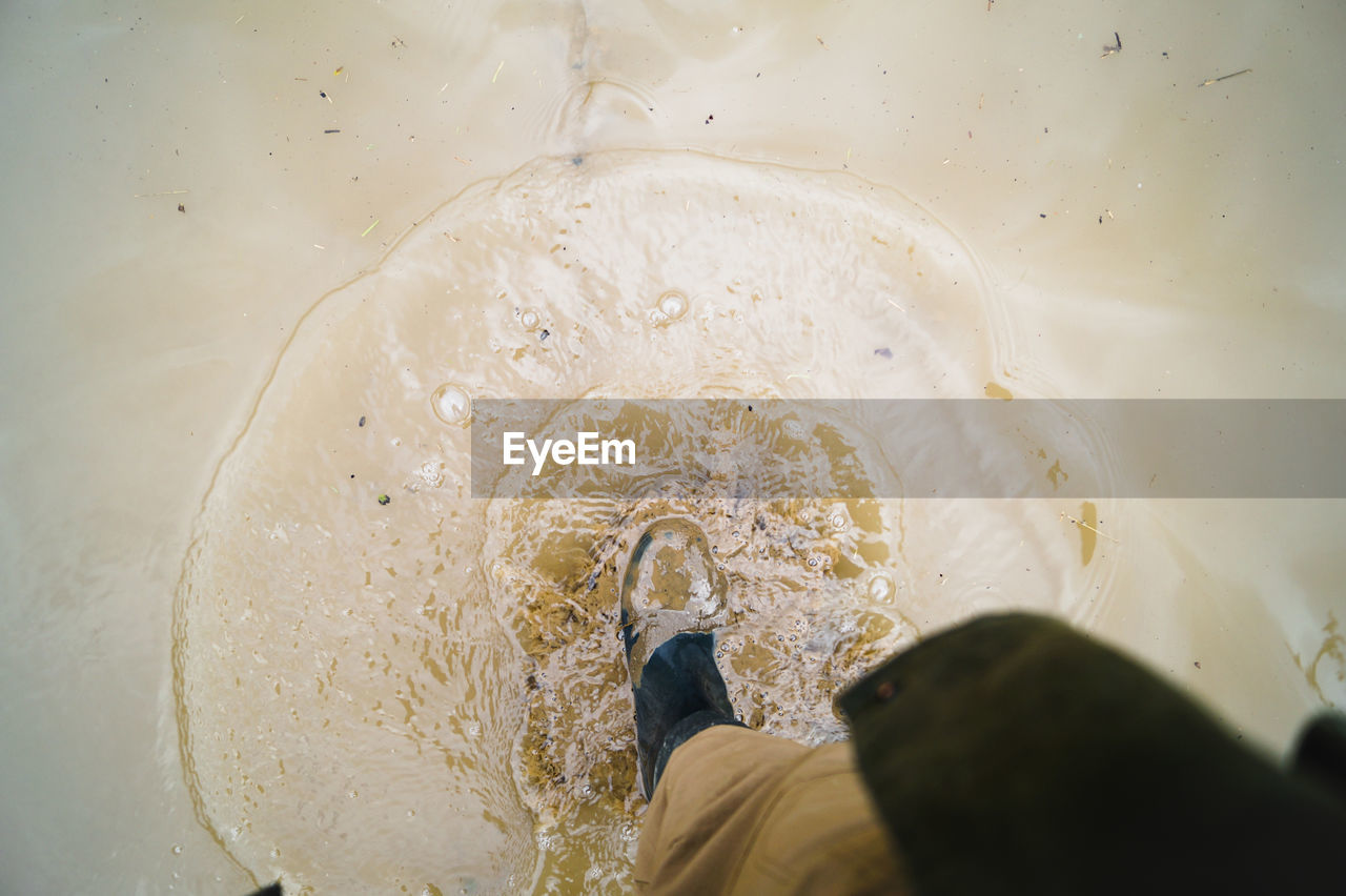 Low section of man walking on muddy field