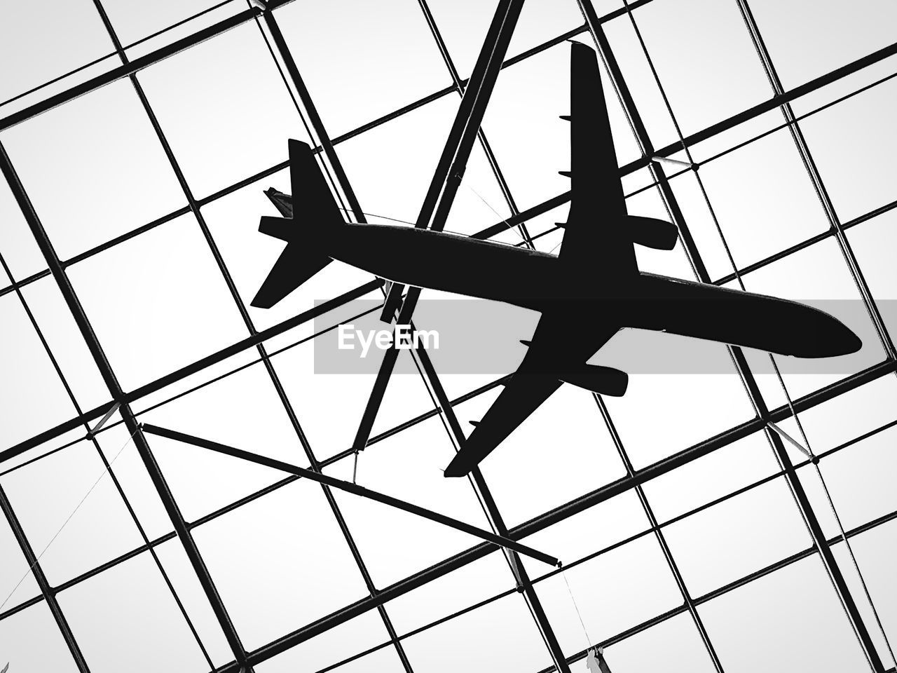 Low angle view of toy airplane hanging from glass ceiling at frankfurt airport