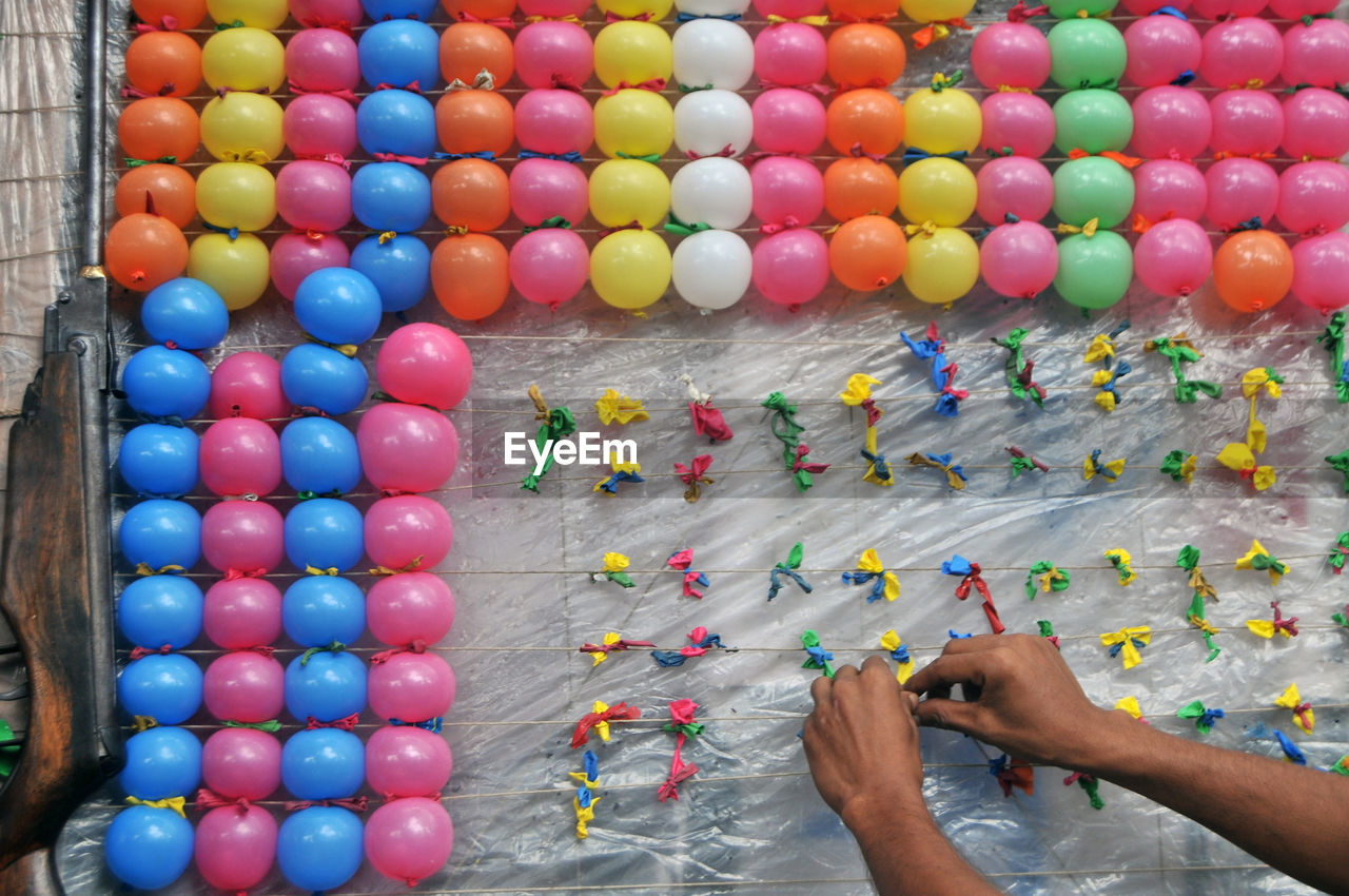 Cropped hand removing damaged balloons on string at arcade game