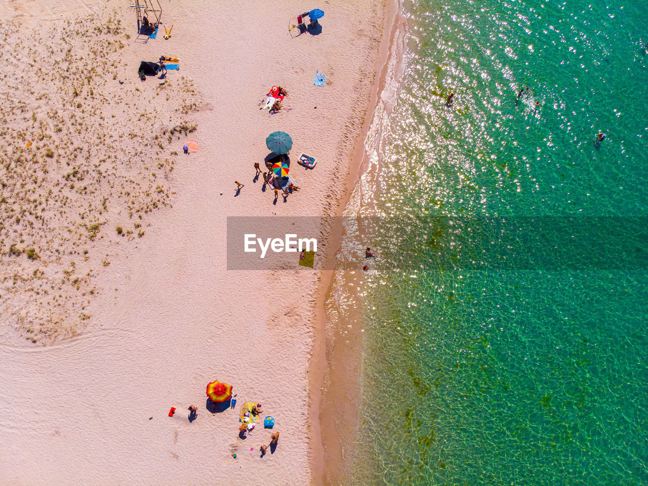Aerial view of a sandy beach with people resting and parasols. view from above