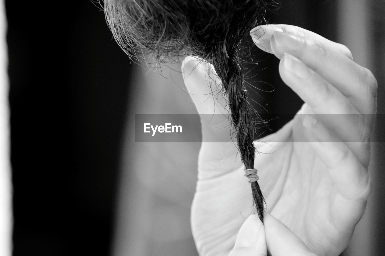 Cropped hands of woman holding braided hair