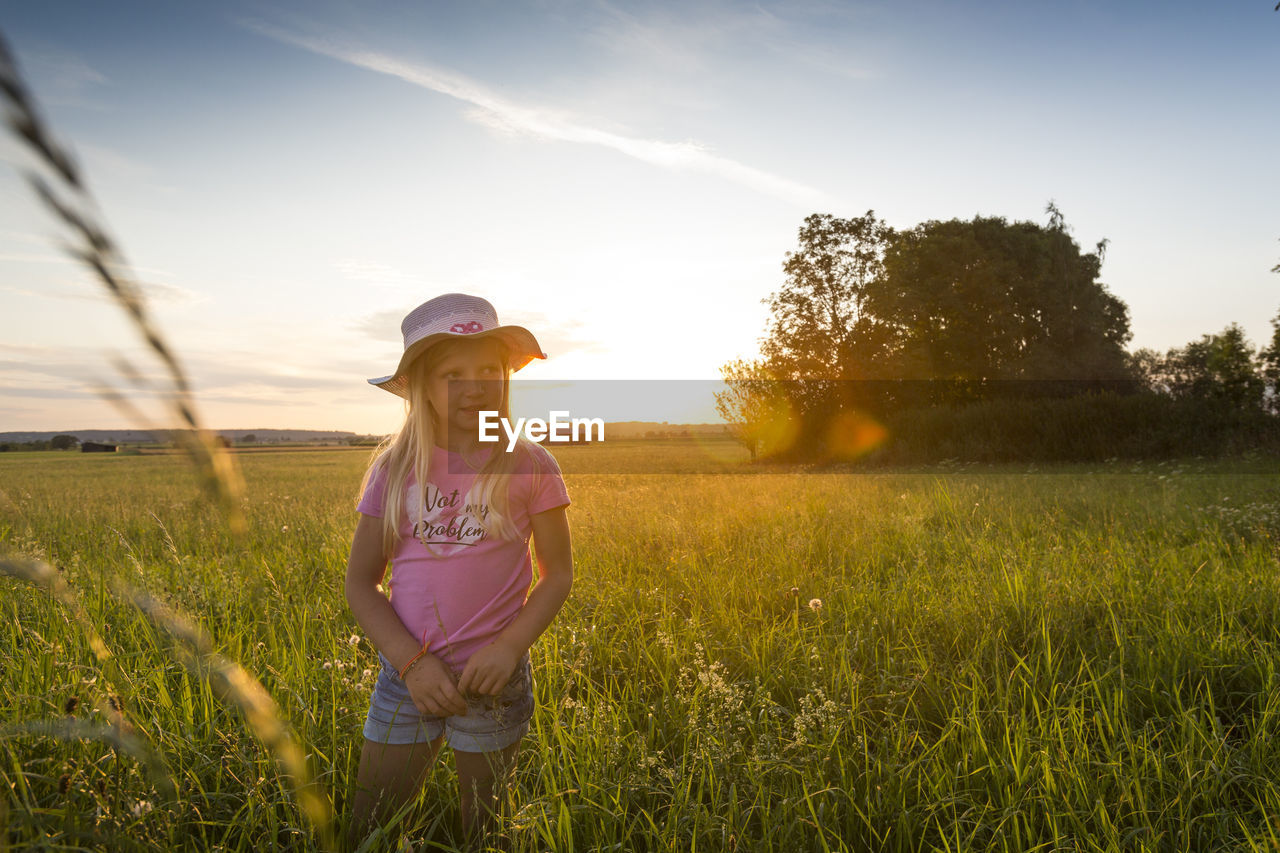 FULL LENGTH OF WOMAN WEARING HAT ON FIELD AGAINST SKY