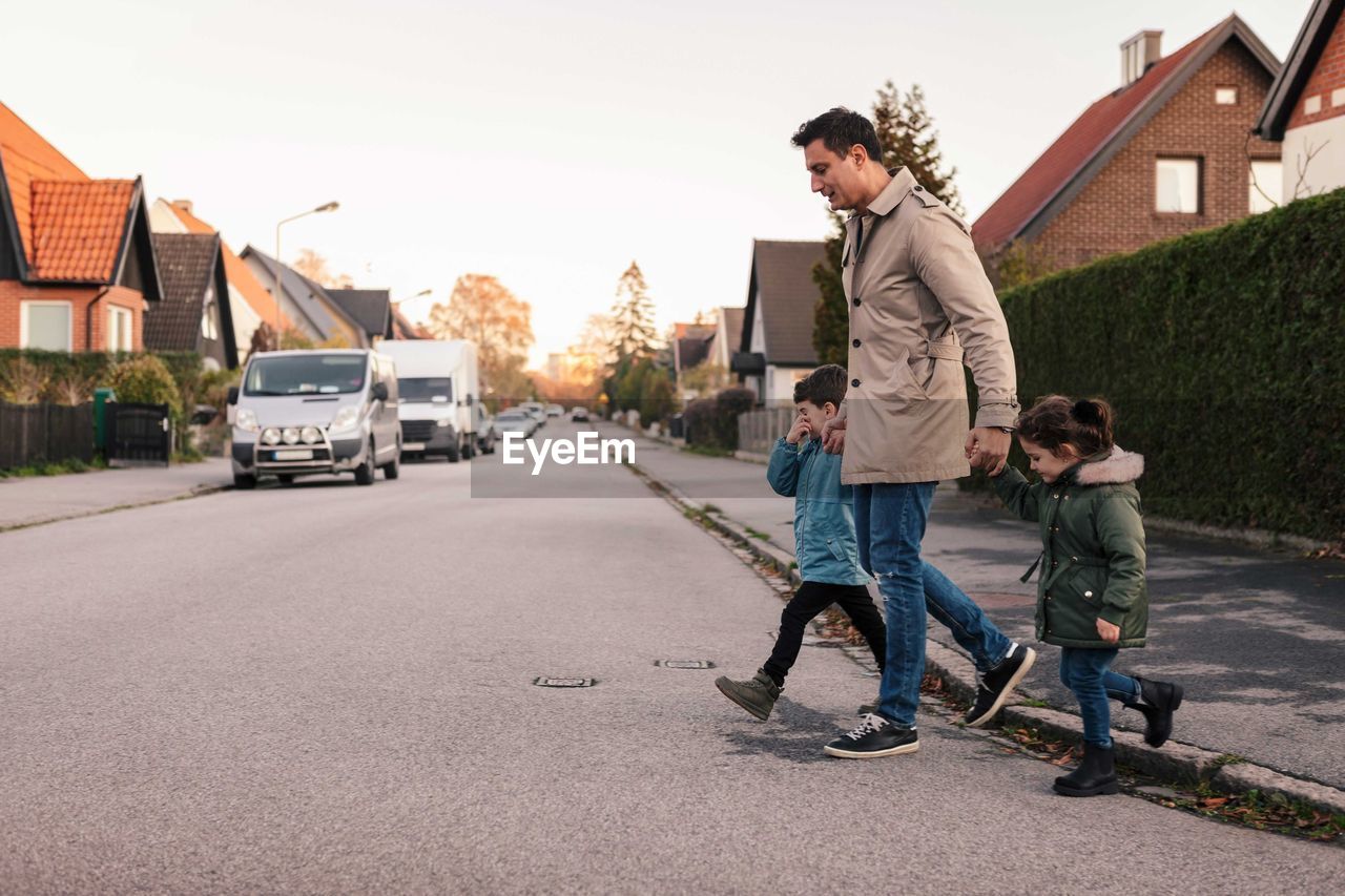 Father crossing footpath with children during autumn