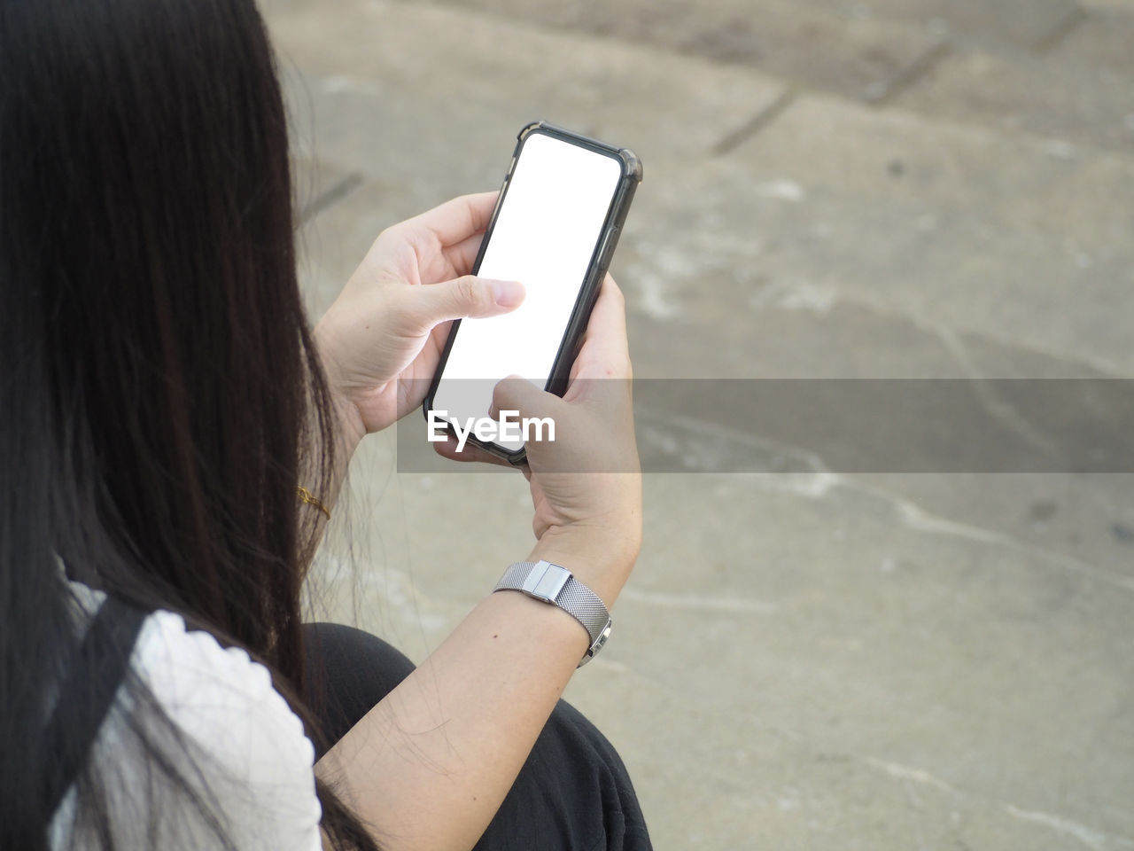REAR VIEW OF WOMAN USING MOBILE PHONE OUTDOORS