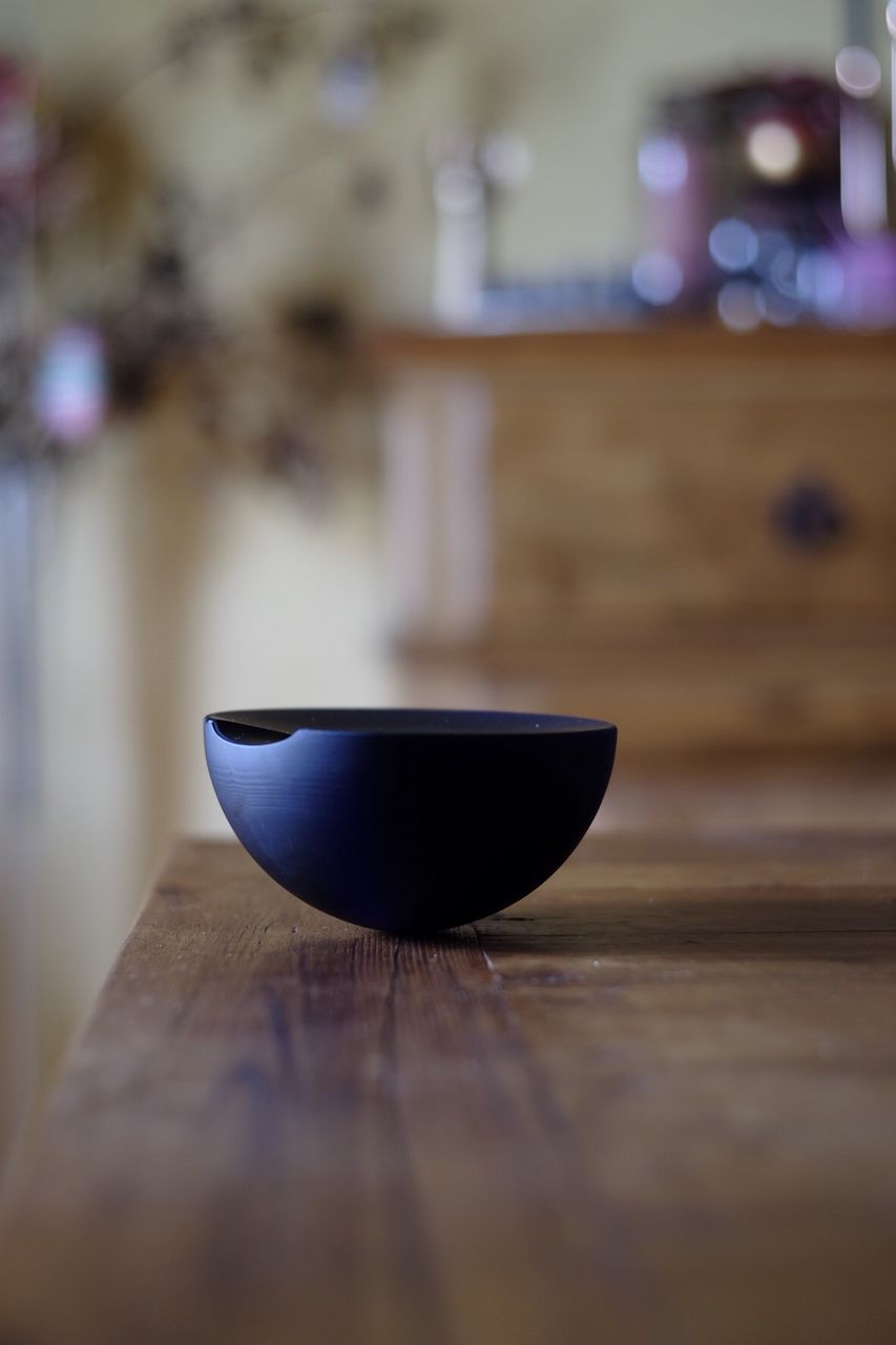 Black bowl on wooden table at home